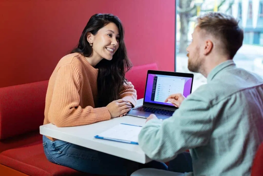 un homme et une femme assis à une table avec un ordinateur portable