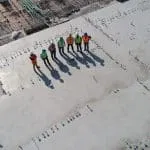 sept travailleurs de la construction debout sur un terrain blanc travaillant en interim à la semaine